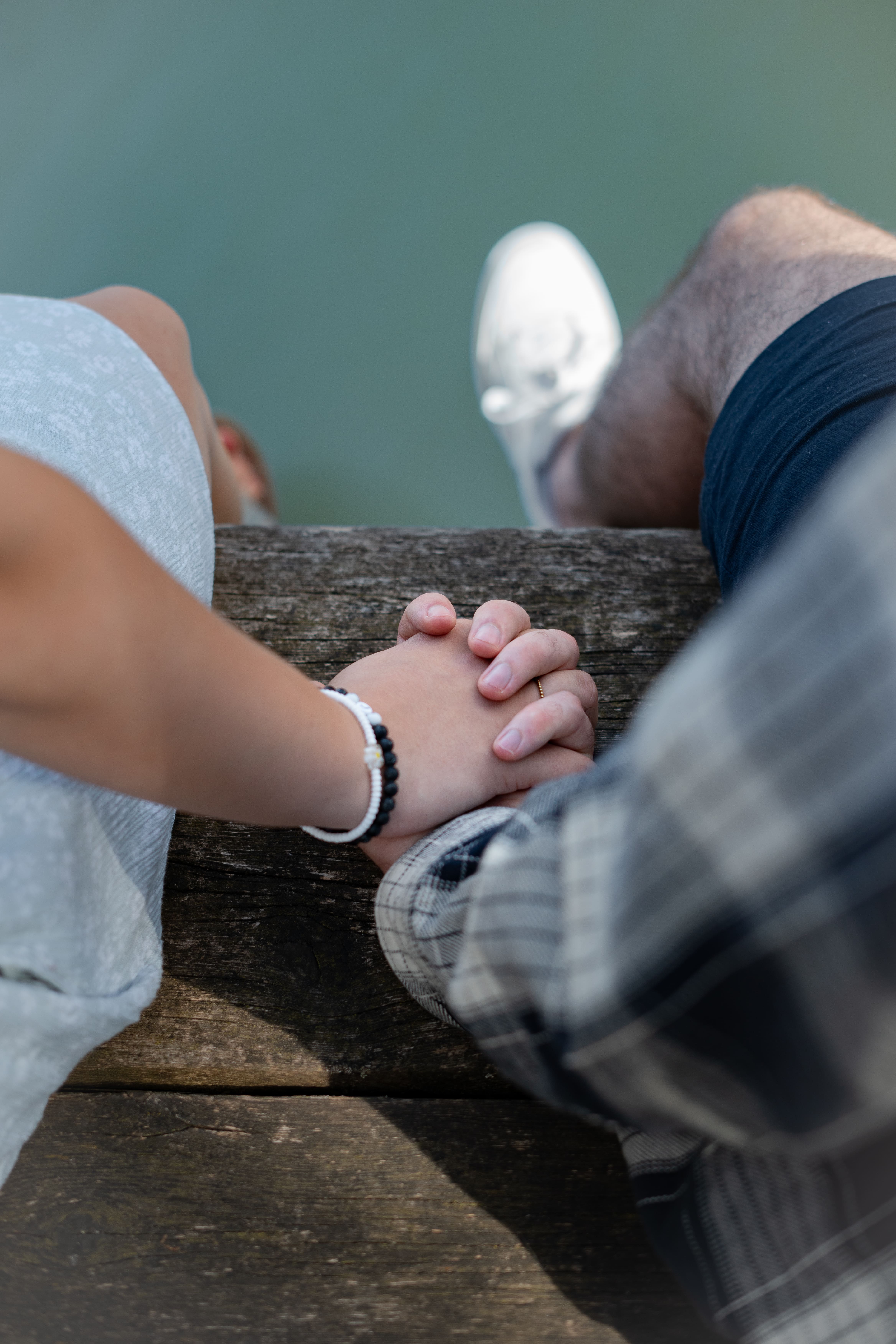 Paar hält sich liebend an der Hand auf dem Steg am Wasser